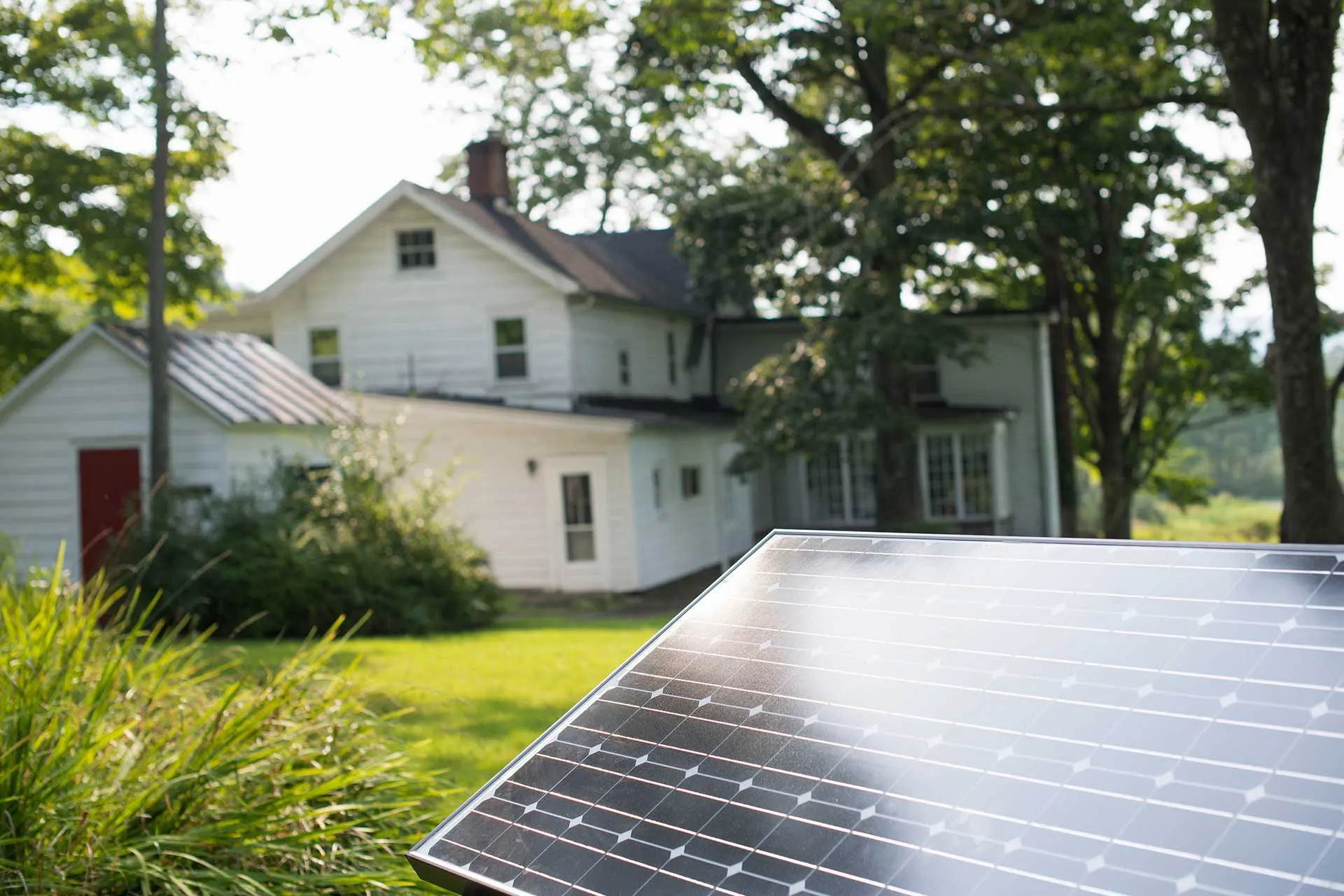 Solarmodul vor einem Wohnhaus mit Garten